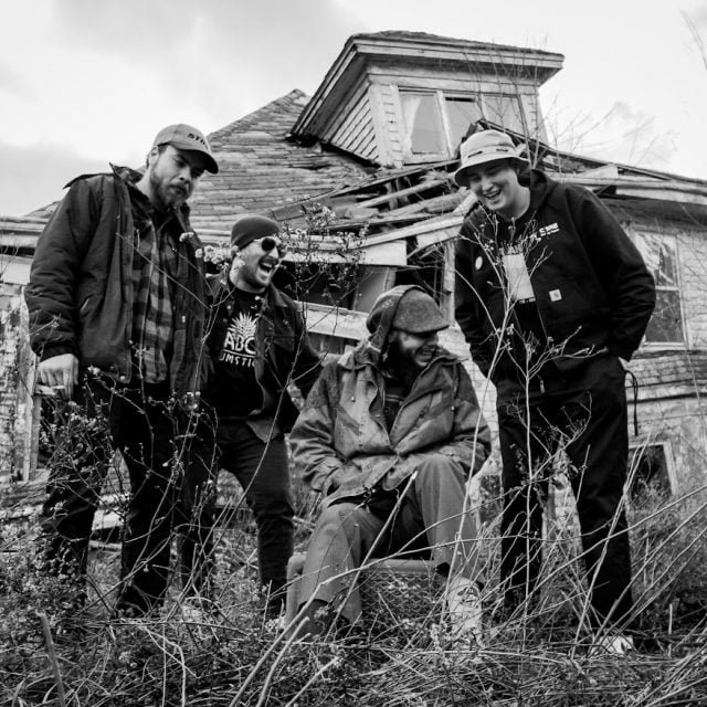 Os 4 integrantes da Baited em cenário aberto e foto em preto e branco.