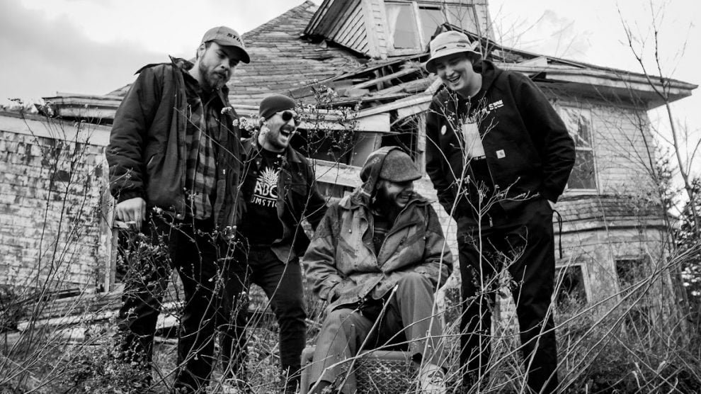 Os 4 integrantes da Baited em cenário aberto e foto em preto e branco.