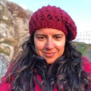 mulher branca, de cabelos longos e boina rosa escuro.