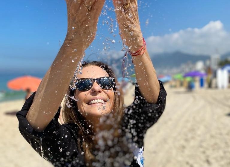 Mulher na praia, com as mãos em direção ao céu