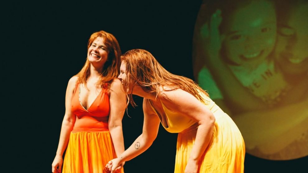 Duas mulheres vestidas de roupa laranja